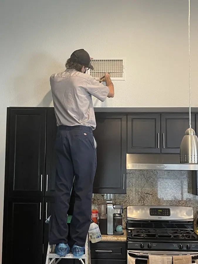 Technician inspecting an air vent during HVAC service in Los Alamos